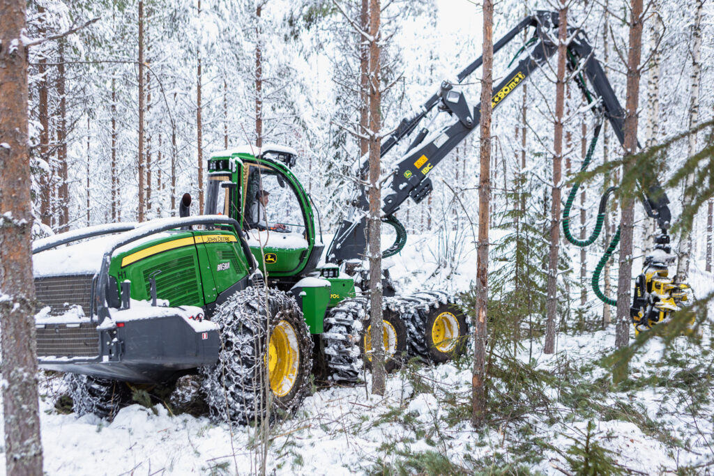 Vihreä metsäkone harventaa metsää.